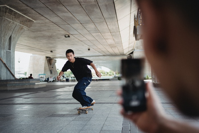 A man capturing an image of a skateboarder.